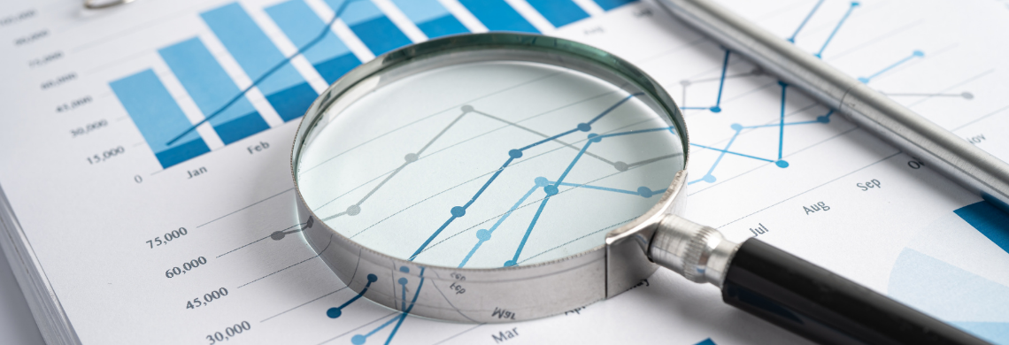 Eine Lupe liegt auf einem Blatt Papier mit Grafiken drauf.